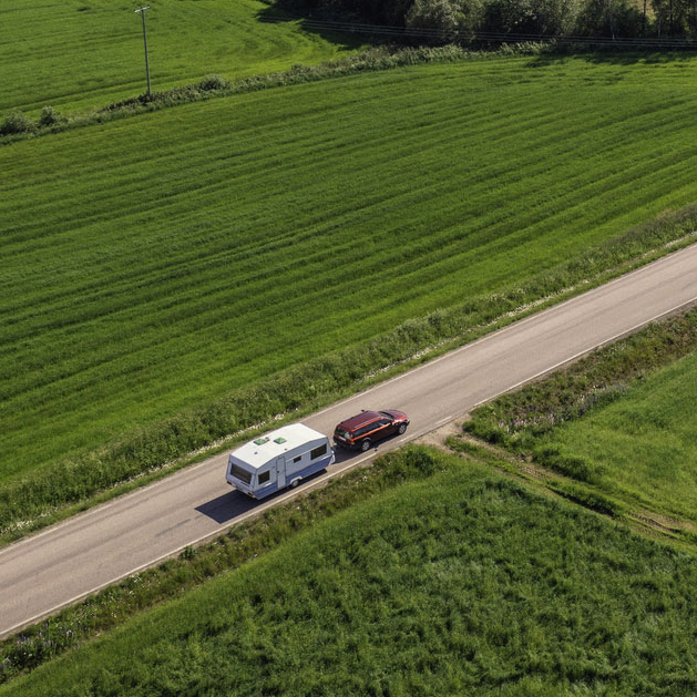 Car With Caravan Driving Through Farmland